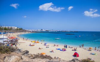 Bañistas en una playa de aguas turquesas y arena fina bajo un cielo despejado, ilustrando la guía con las mejores playas de España de 2026.