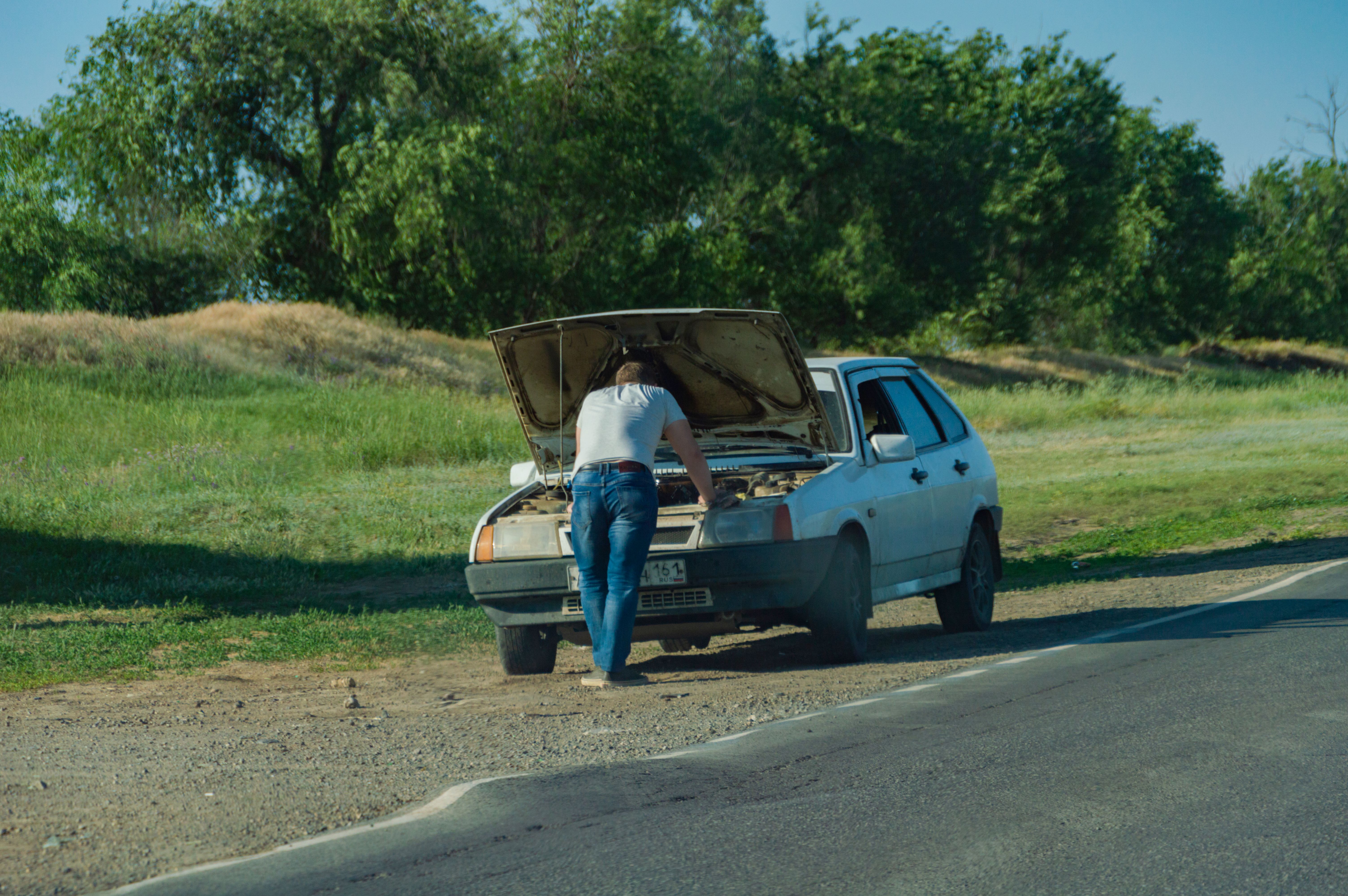 Las averías en el coche son uno de los imprevistos financieros más caros Hombre contempla el capó abierto del coche debido a una avería