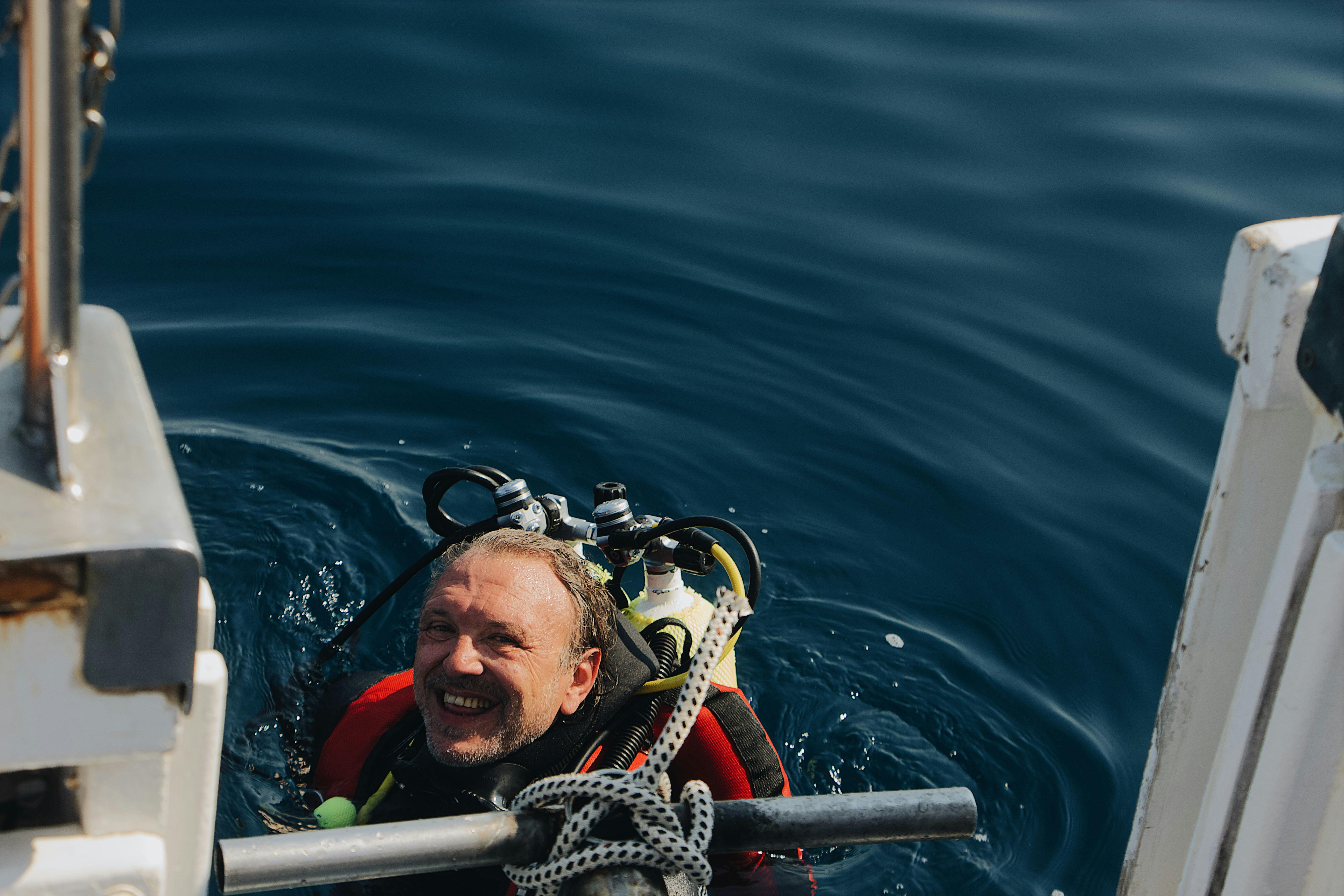 Submarinista terminando su inmersión Un buceador sale del agua sonriendo antes de subir al barco