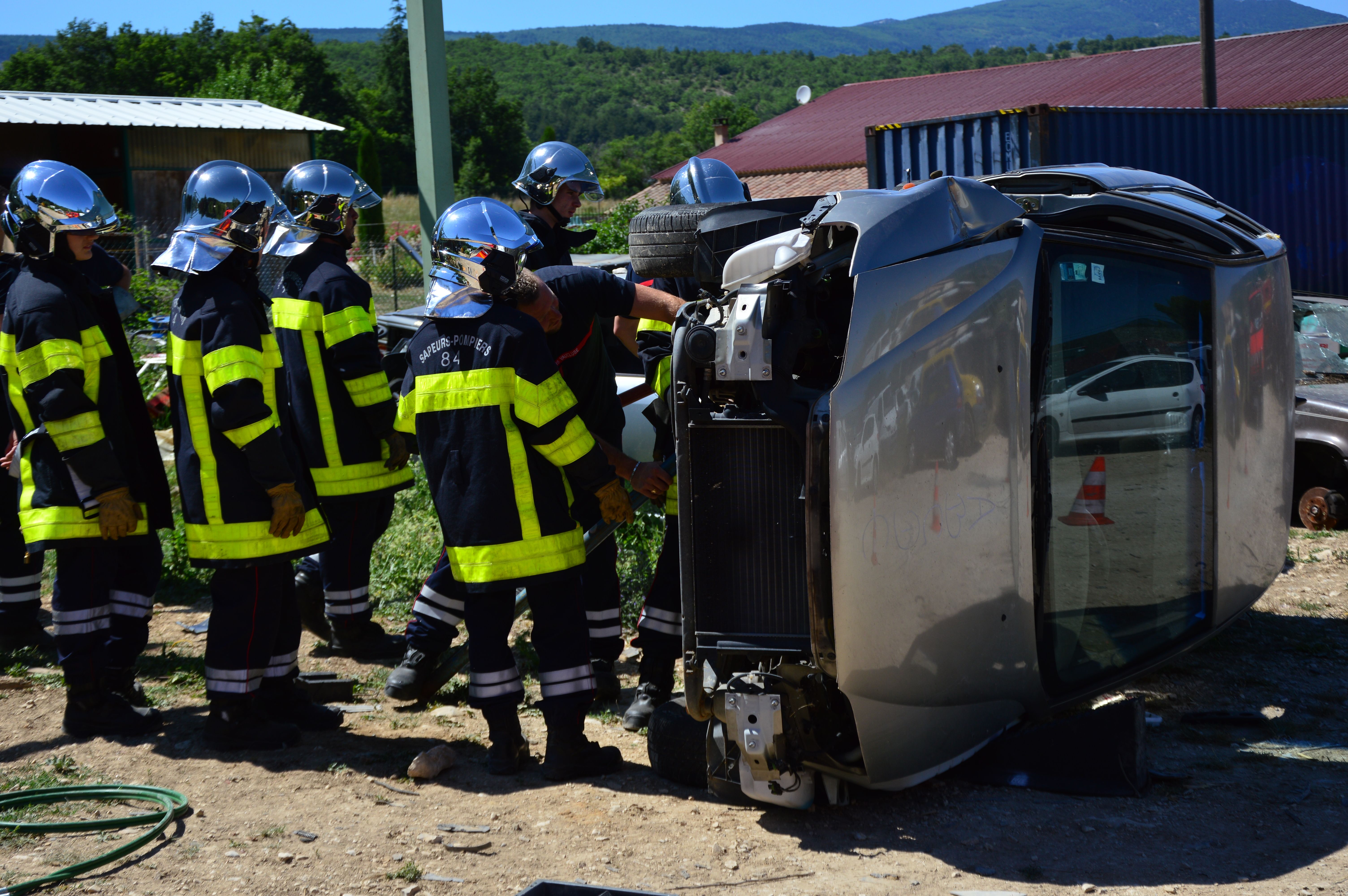 Distinción entre siniestro total económico y pérdida total física en vehículos. Bomberos evaluando un vehículo volcado tras un accidente grave, representando la diferencia entre la declaración económica de siniestro total y el daño estructural de pérdida total.