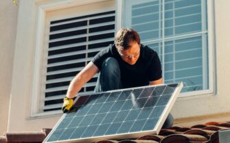 Un hombre, instalando una placa solar, el tejado de una casa