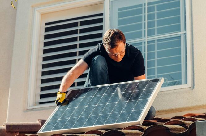 Un hombre, instalando una placa solar, el tejado de una casa