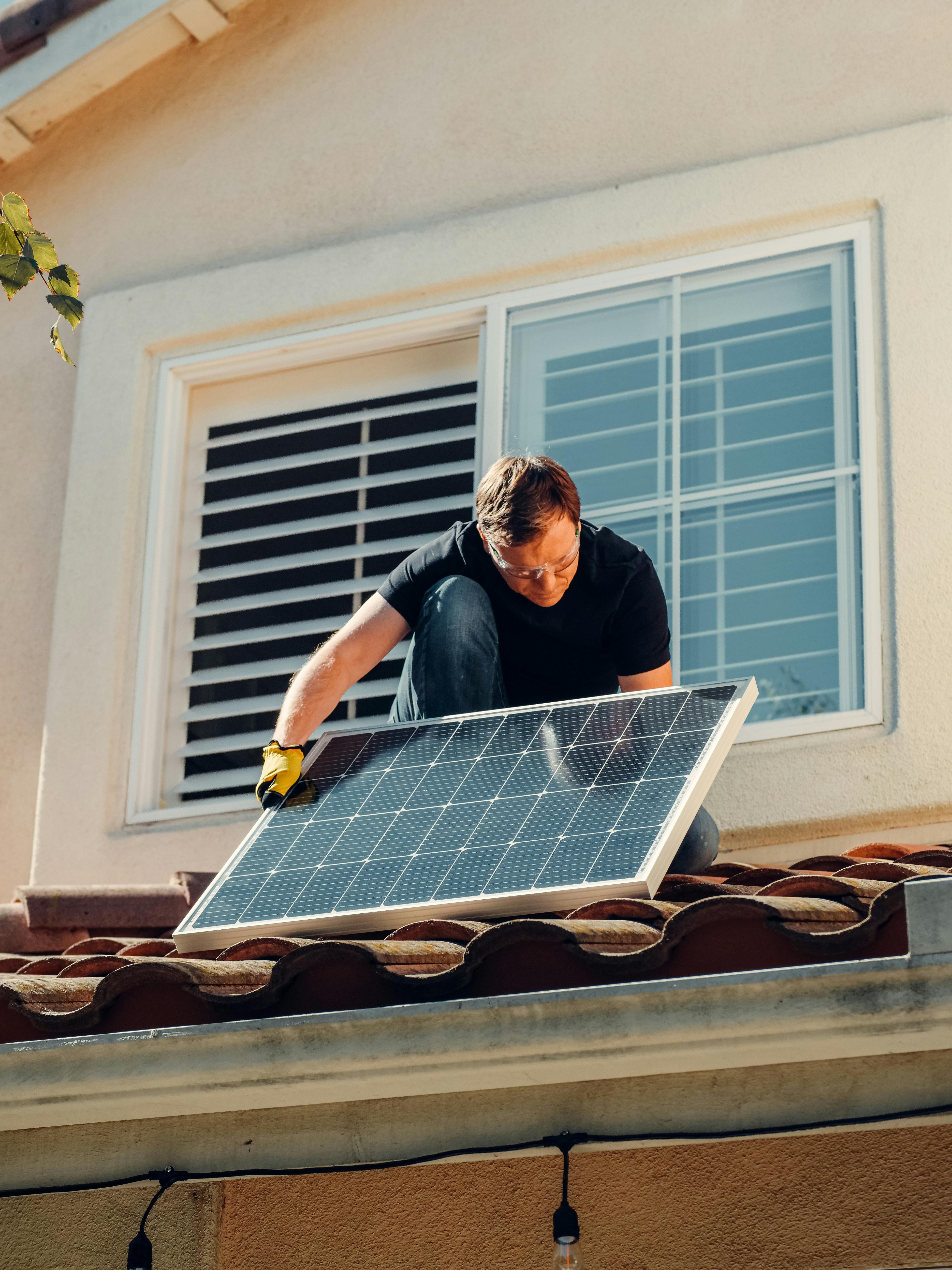Un hombre, instalando una placa solar, el tejado de una casa