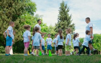 Un grupo de niños en círculo junto a sus monitores durante una actividad al aire libre, ilustrando el análisis del precio de los campamentos de verano en 2026.