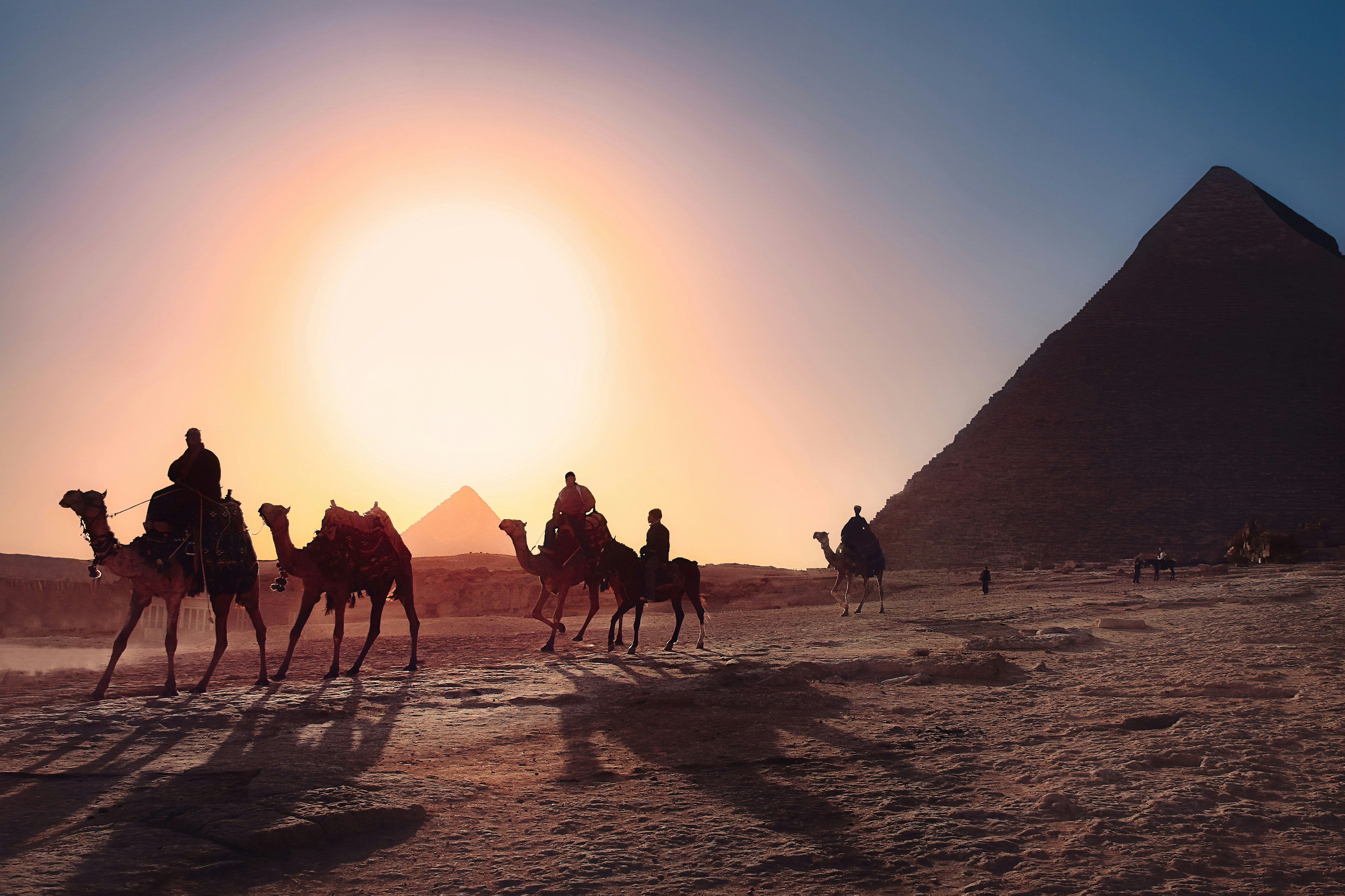 Tour a camello por las pirámides de Egipto Cinco personas montadas en camello junto a una pirámide de Egipto