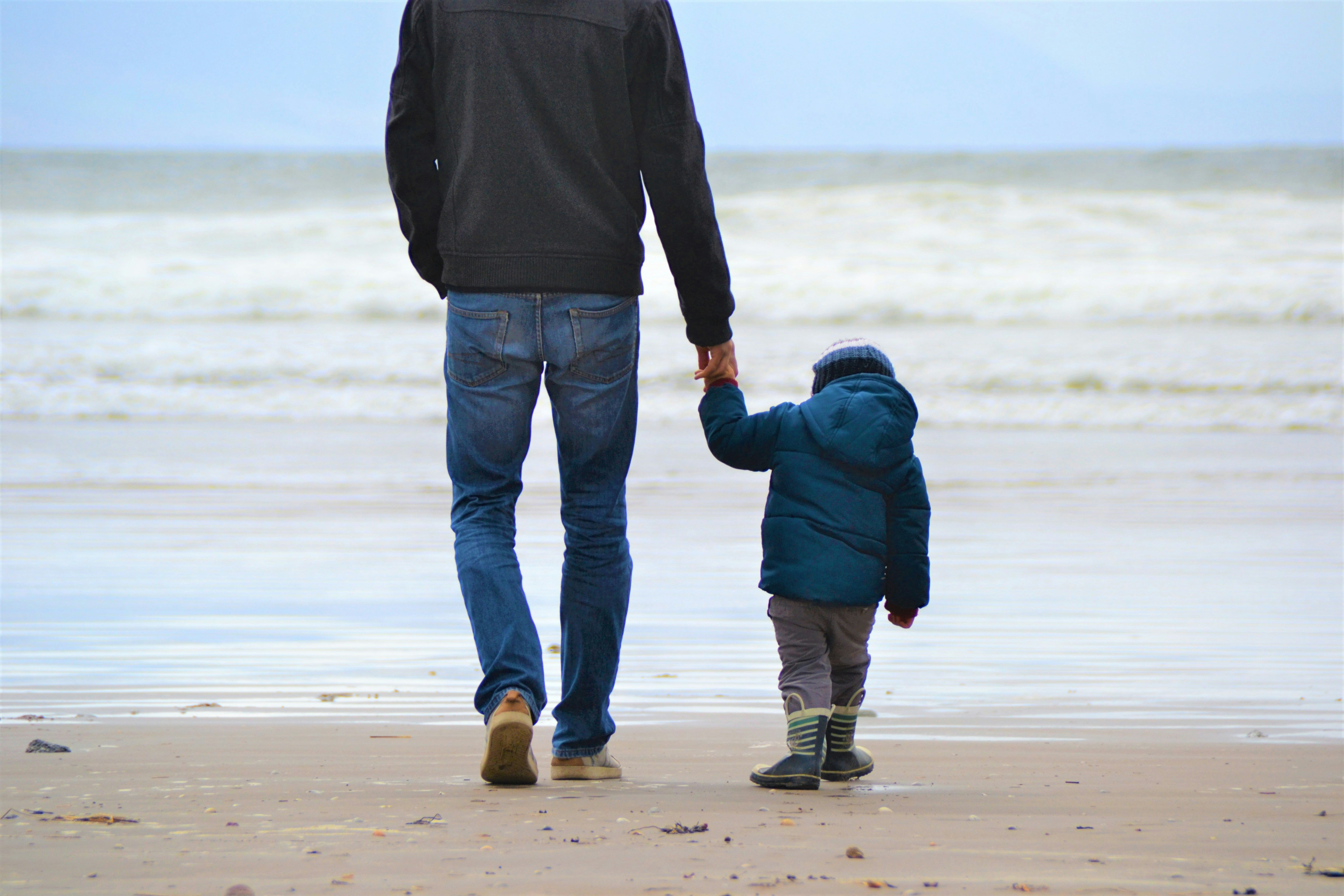 Las vacaciones con los hijos, uno de los gastos más recortados Un padre y su hijo pequeño caminan frente al mar dados de la mano