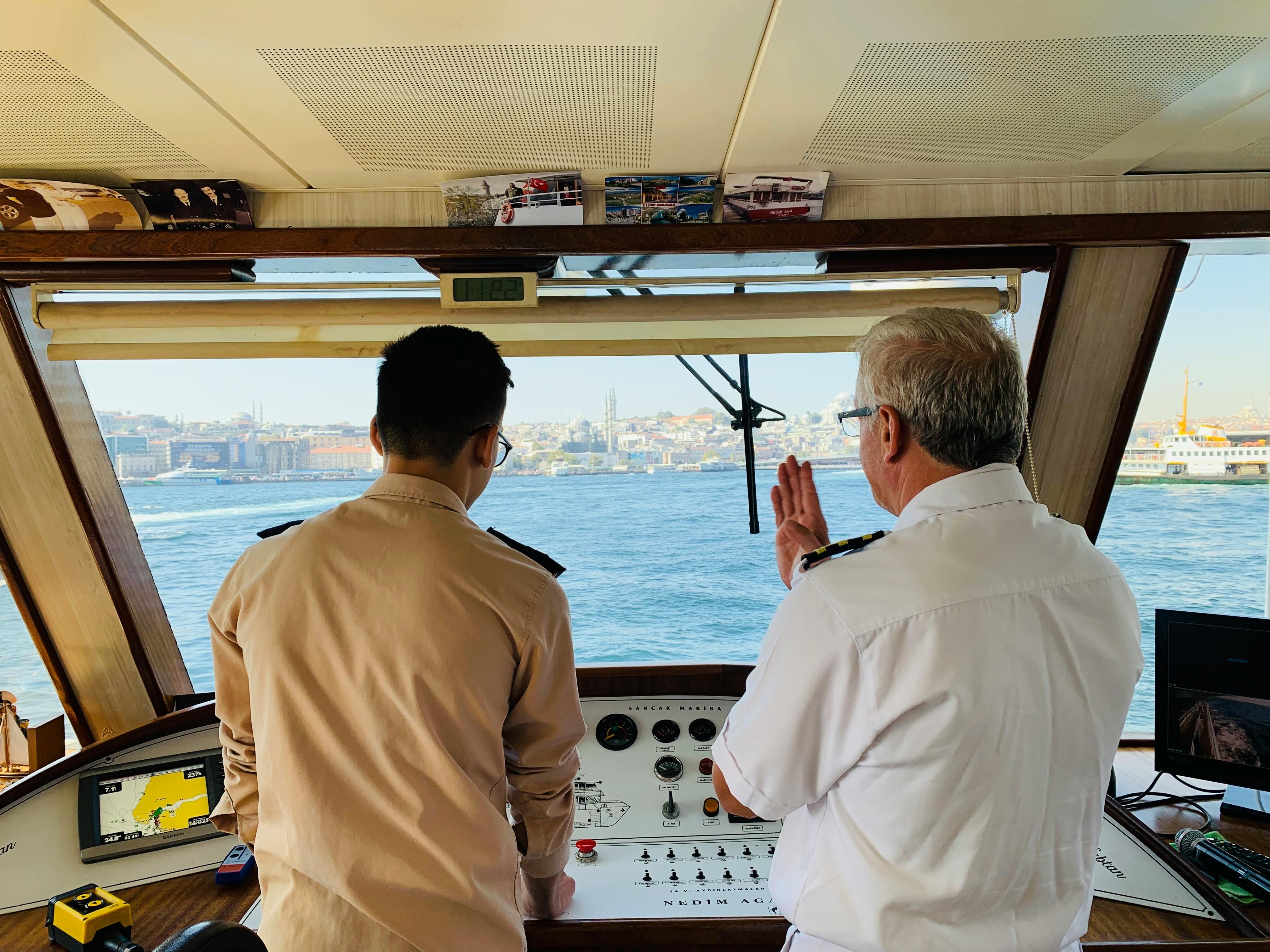 Formación y prácticas de navegación para Capitán de Yate Dos profesionales en el puente de mando de una embarcación realizando las prácticas para el título de Capitán de Yate