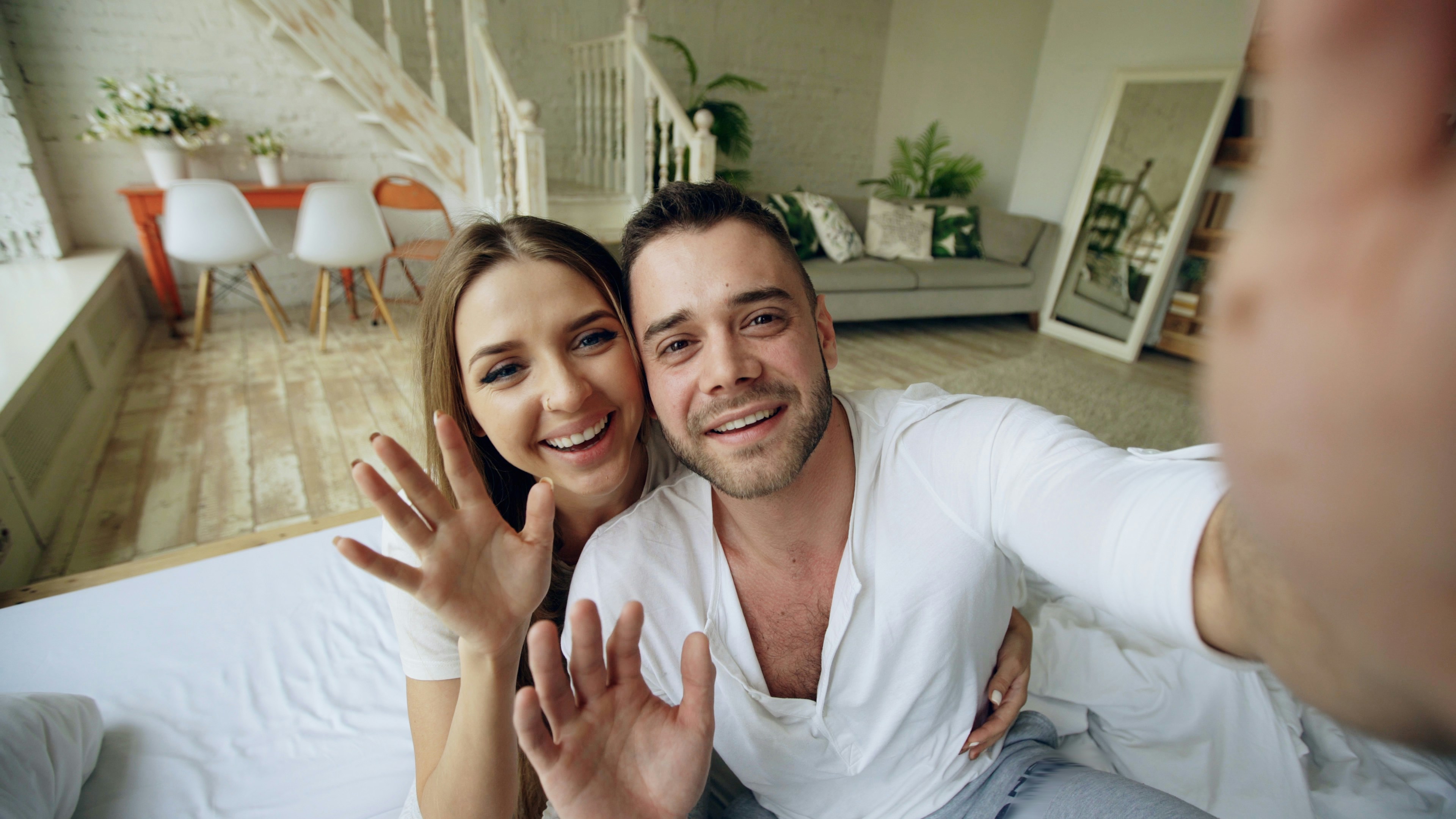 Una pareja sonriente mirando a cámara Un selfie de una pareja de alquiler en el salón